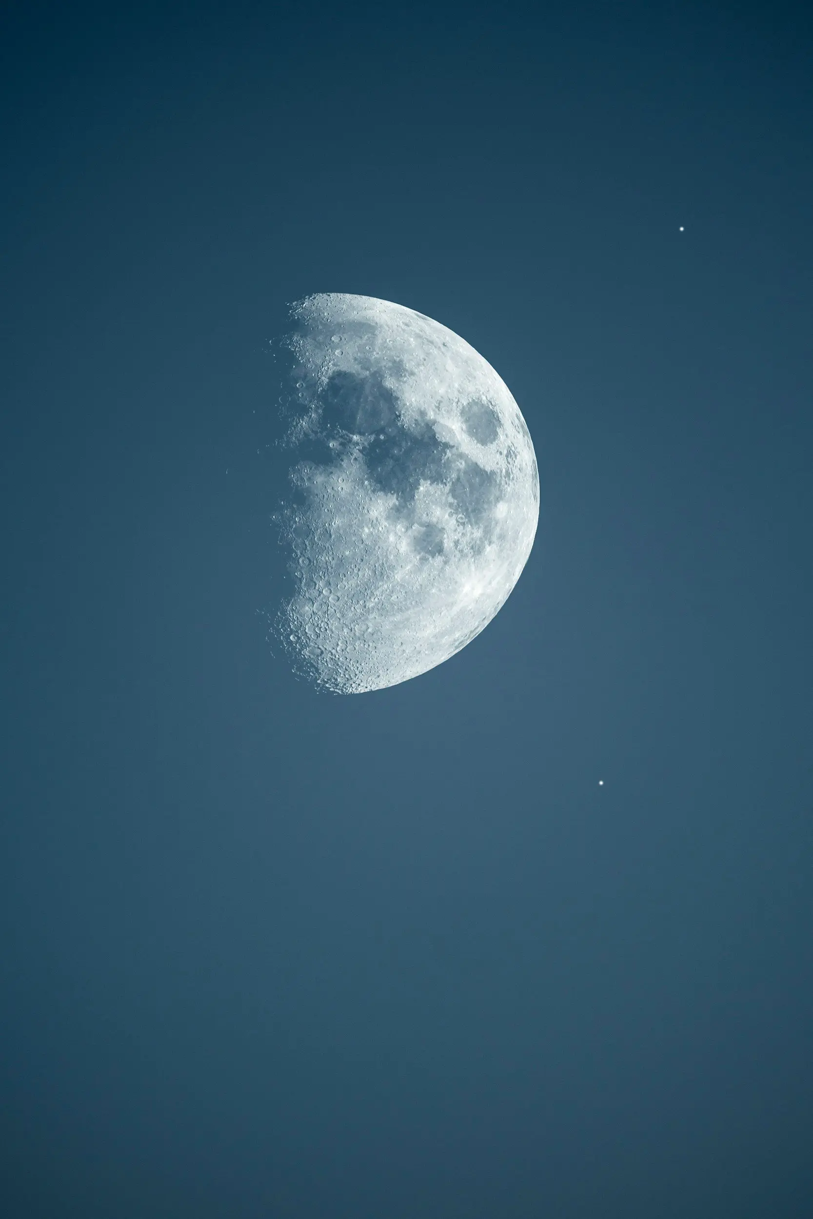 A waxing gibbous moon in a deep blue evening sky